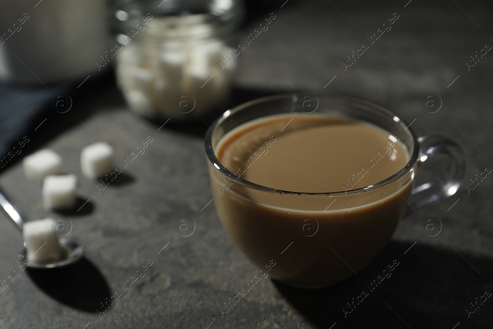 Photo of Tasty coffee with milk in cup and sugar cubes on grey table, closeup