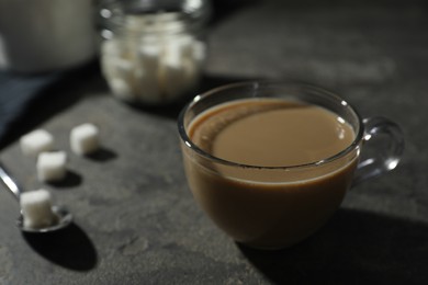 Photo of Tasty coffee with milk in cup and sugar cubes on grey table, closeup