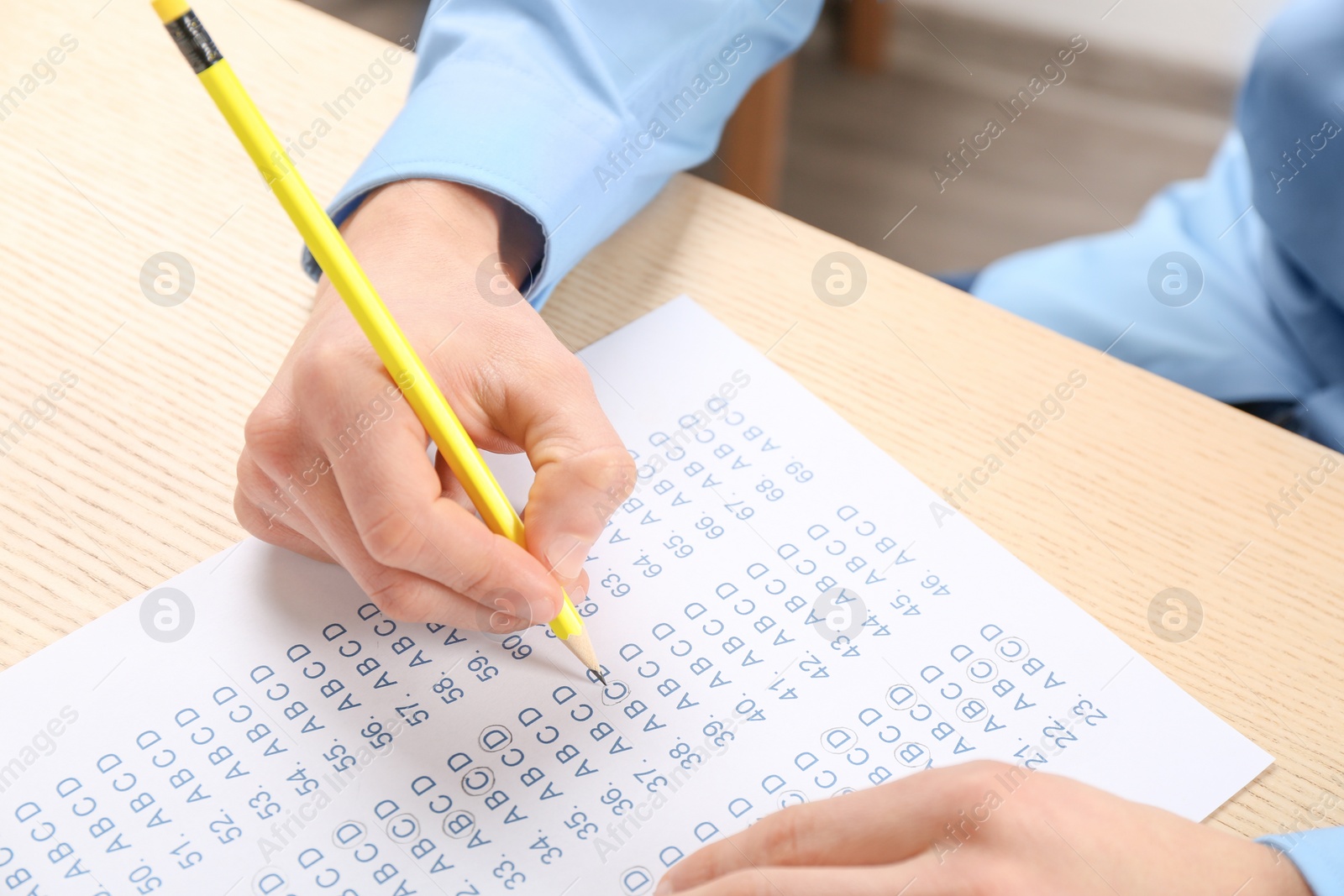 Photo of Student filling answer sheet at table, closeup