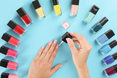 Photo of Woman applying nail polish on color background, above view