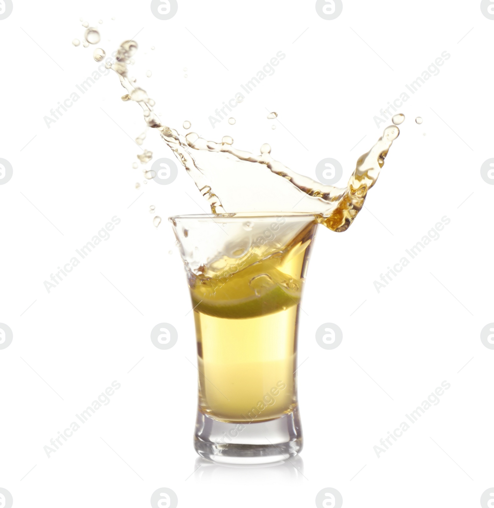 Photo of Splashing Mexican Tequila in shot glass with lime slice isolated on white