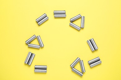 Recycling symbol made of batteries on yellow background, top view