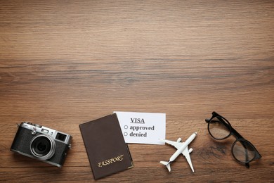 Flat lay composition with passport, toy plane and glasses on wooden table, space for text. Visa receiving