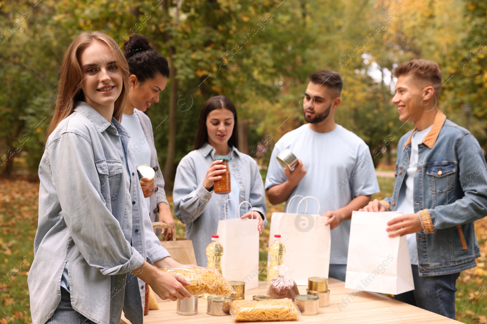 Photo of Group of volunteers packing food products at table in park