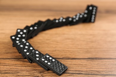 Photo of Black domino tiles falling on wooden table