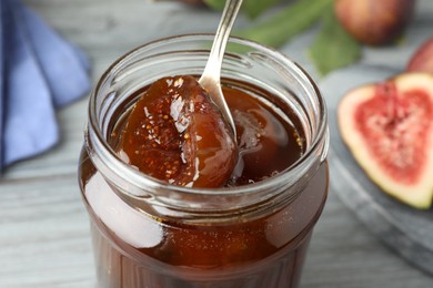 Jar of tasty sweet fig jam on table, closeup