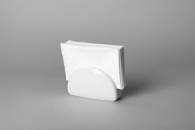 Photo of Ceramic napkin holder with paper serviettes on gray background