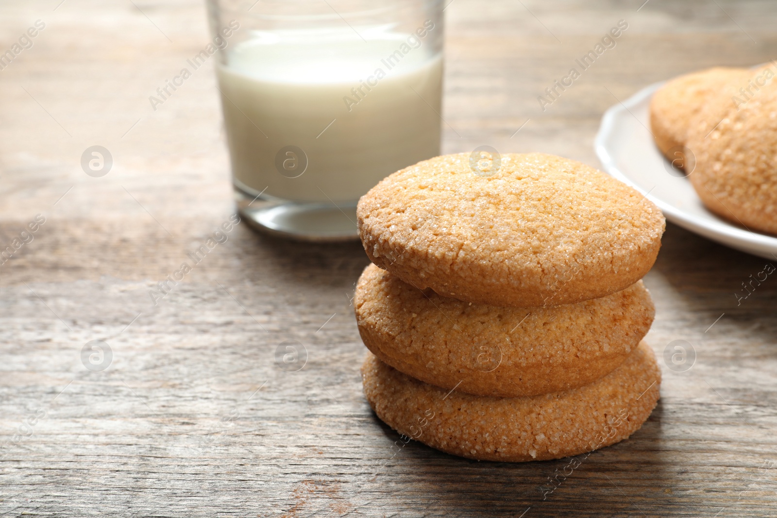 Photo of Tasty Danish butter cookies and milk on wooden table. Space for text