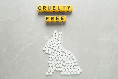 Photo of Cubes with text Cruelty Free and rabbit figure of pills on light marble table, flat lay. Stop animal tests