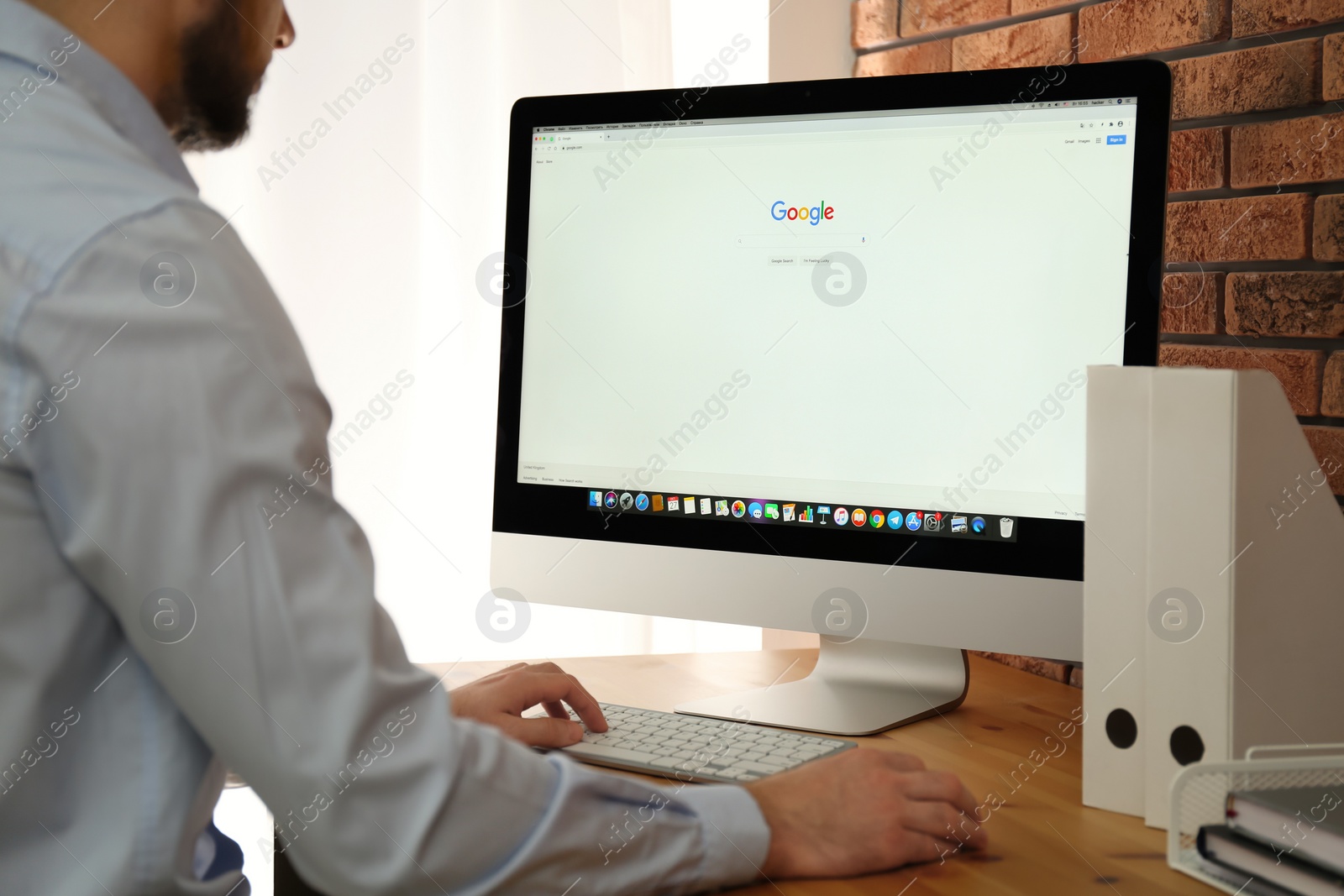 Photo of MYKOLAIV, UKRAINE - OCTOBER 27, 2020: Man using Google search engine on Apple iMac PC at table indoors, closeup