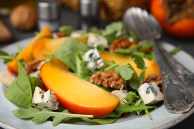 Tasty salad with persimmon, blue cheese and walnuts served on table, closeup