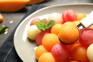 Photo of Melon and watermelon balls with scoop on plate, closeup