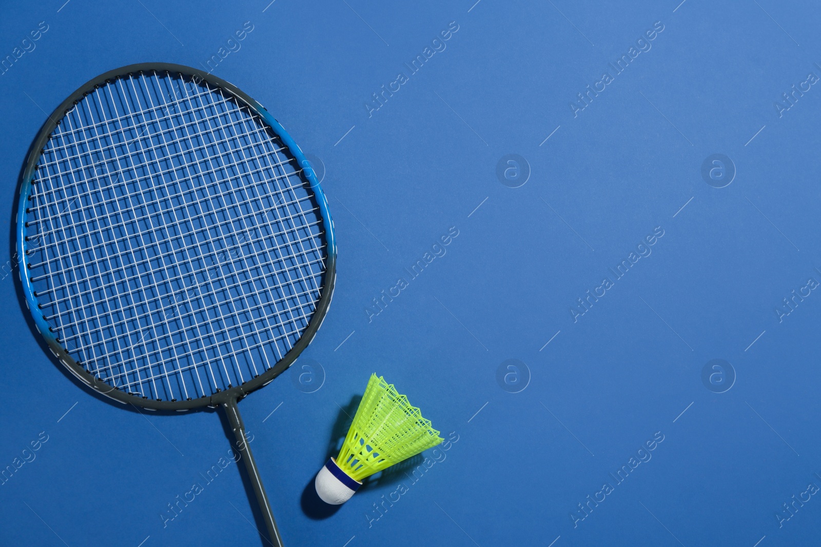 Photo of Badminton racket and shuttlecock on blue background, flat lay. Space for text