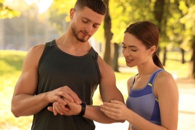 Attractive couple checking pulse after training in park on sunny day