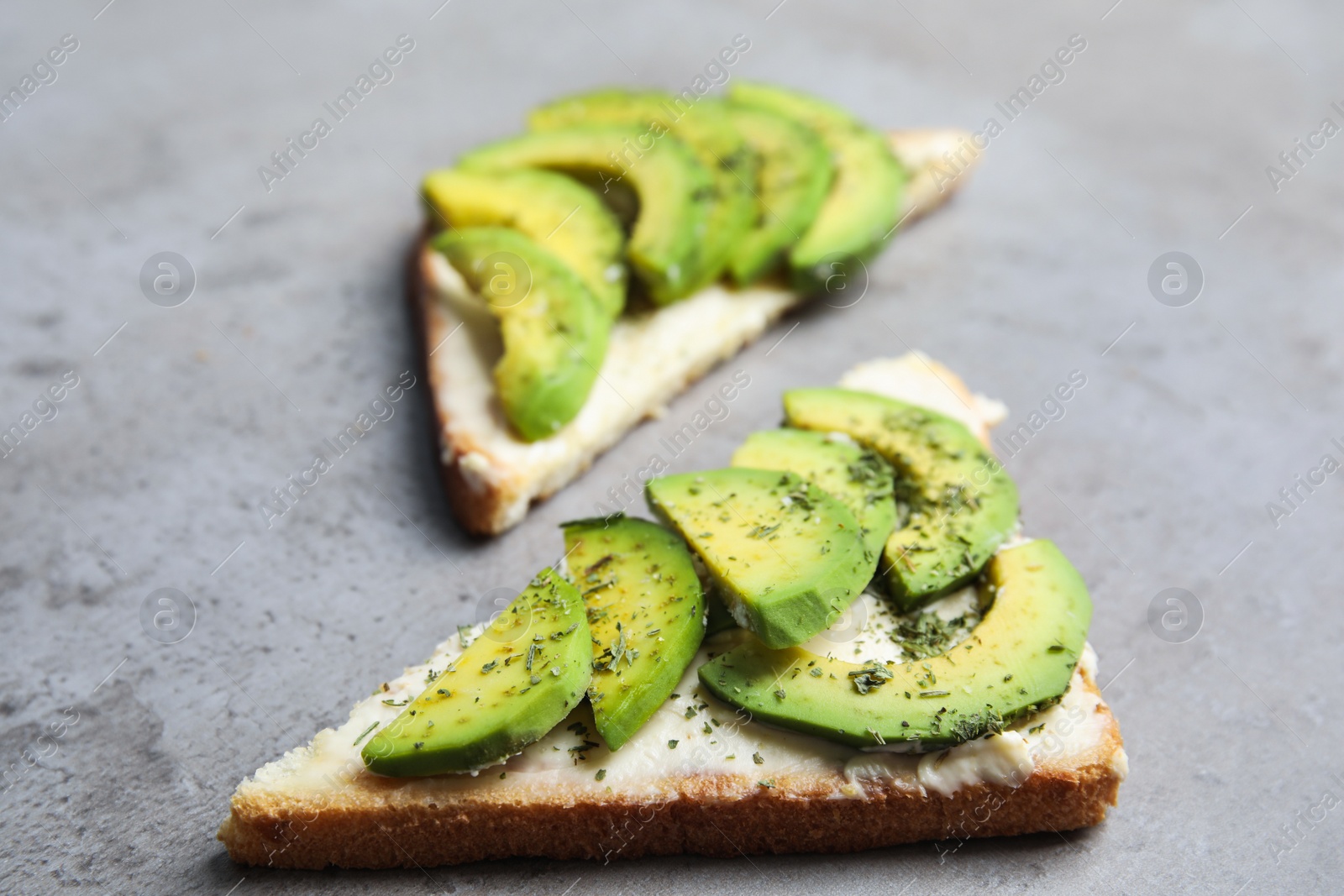 Photo of Tasty avocado toasts on light grey table, closeup