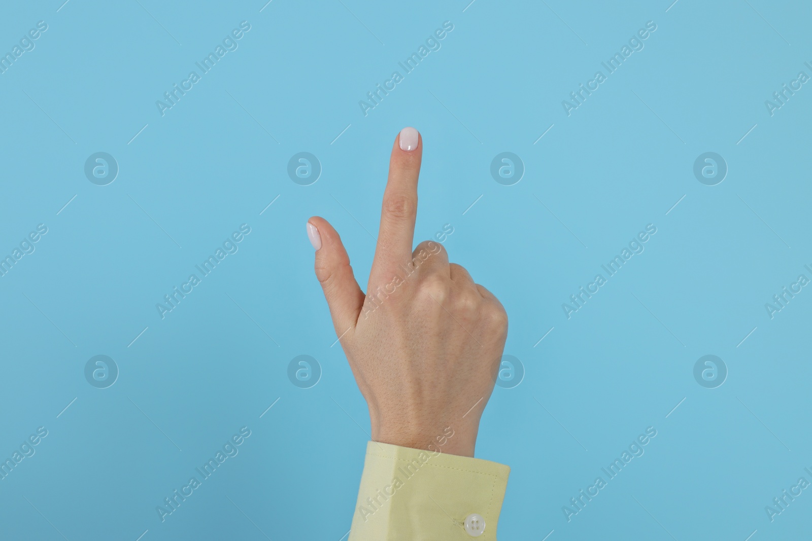 Photo of Woman pointing at something against light blue background, closeup on hand