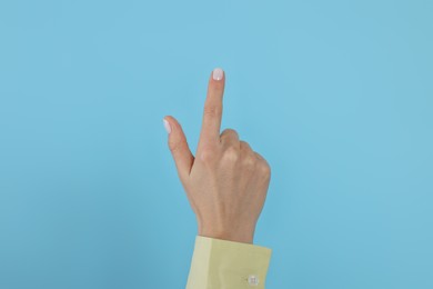 Photo of Woman pointing at something against light blue background, closeup on hand