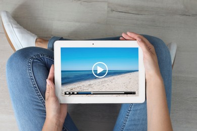 Image of Woman using tablet to watch video on floor at home, closeup