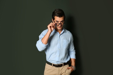 Handsome young man in stylish clothes with glasses on dark background