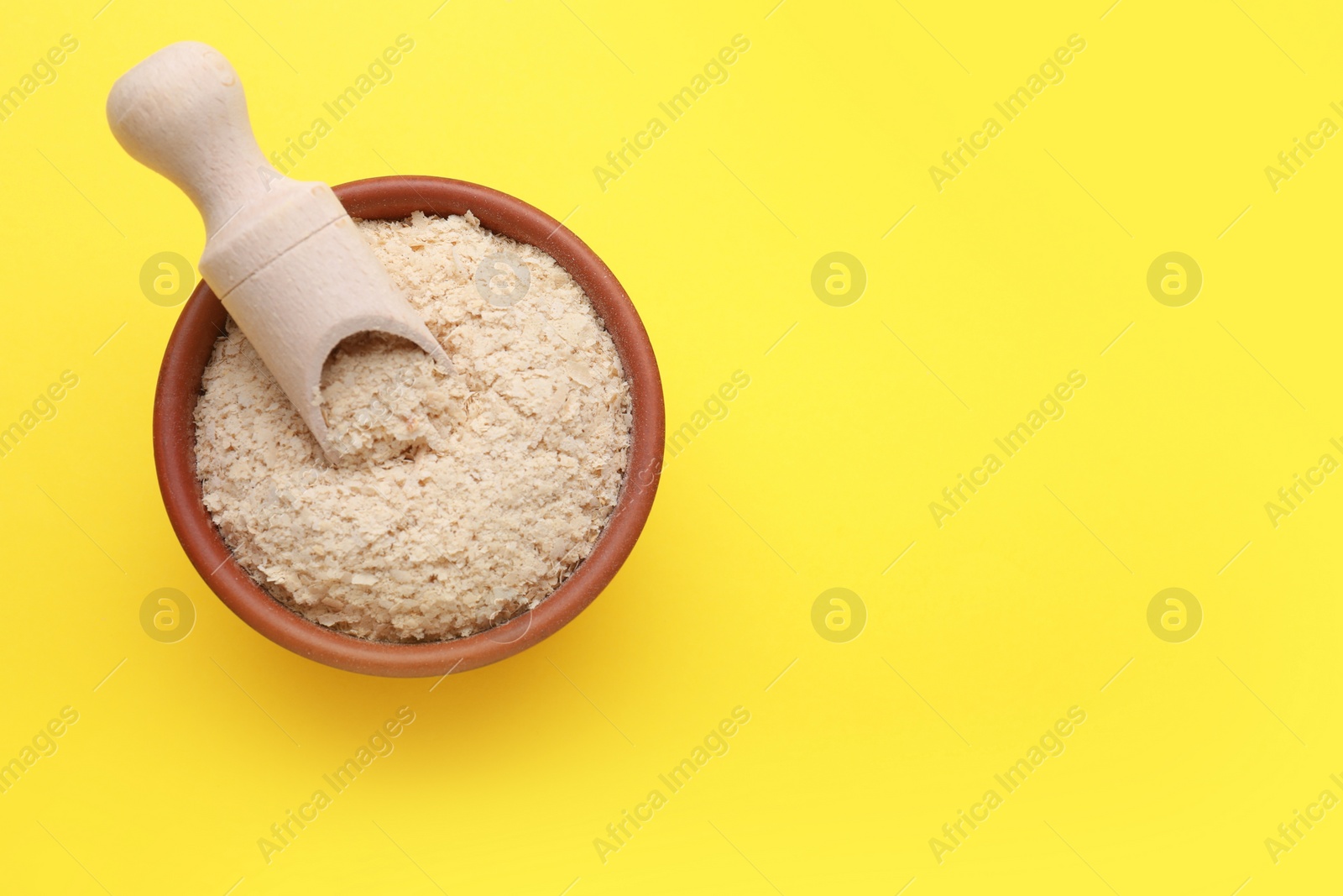 Photo of Beer yeast flakes on yellow background, top view. Space for text