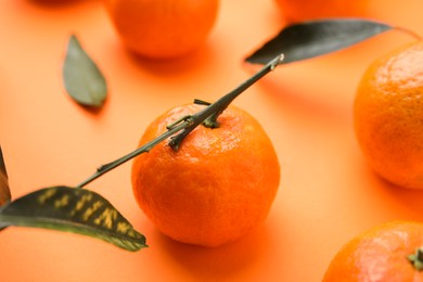 Photo of Fresh ripe tangerines with leaves on orange background, closeup