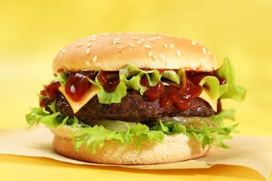 Burger with delicious patty on yellow background, closeup
