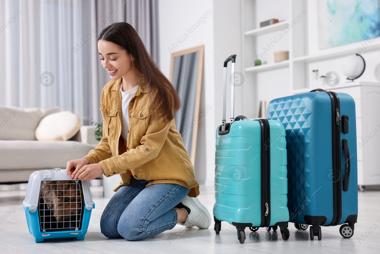 Photo of Smiling woman closing carrier with her pet before travelling indoors