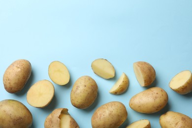 Photo of Fresh raw potatoes on light blue background, flat lay. Space for text