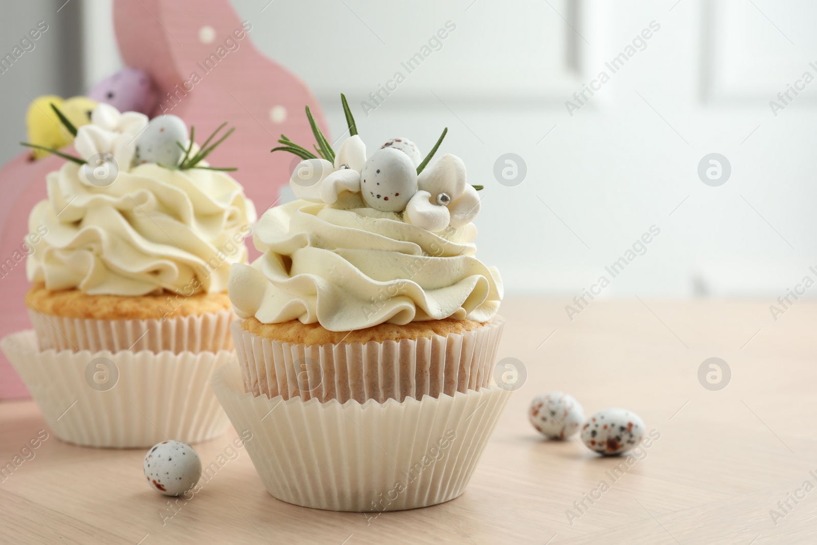 Photo of Tasty Easter cupcakes with vanilla cream on wooden table, space for text