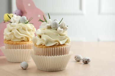 Tasty Easter cupcakes with vanilla cream on wooden table, space for text