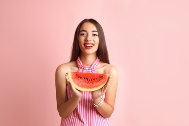 Beautiful young woman posing with watermelon on color background