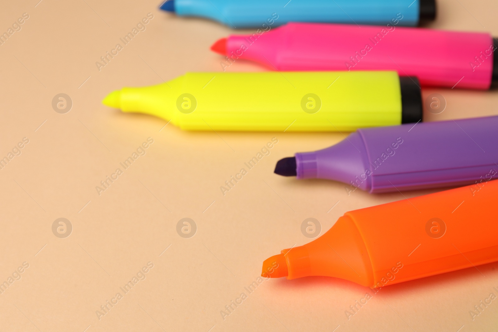Photo of Bright color markers on beige background, closeup. Space for text