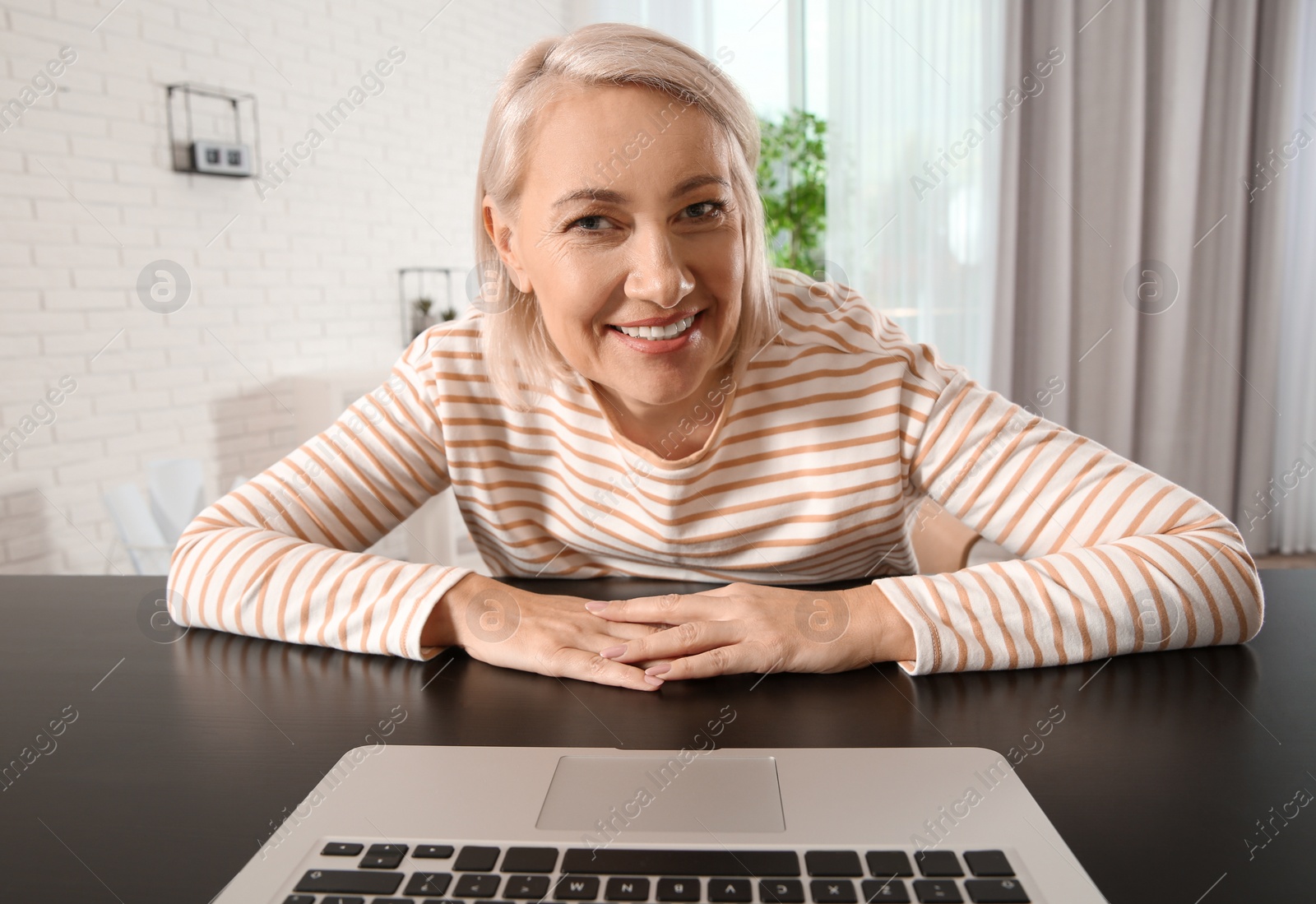 Photo of Mature woman using video chat on laptop at home, view from web camera