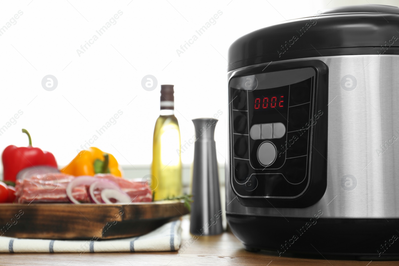 Photo of Modern multi cooker and products on wooden table in kitchen. Space for text