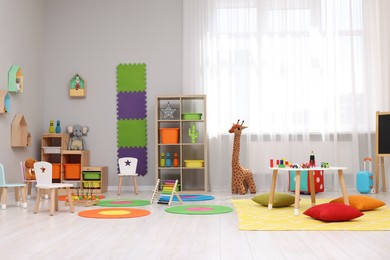 Photo of Child`s playroom with different toys and furniture. Cozy kindergarten interior