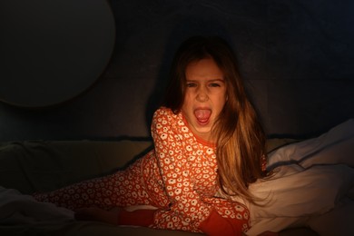 Photo of Childhood phobia. Little girl screaming on bed at home