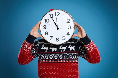Photo of Man with clock on blue background. New Year countdown