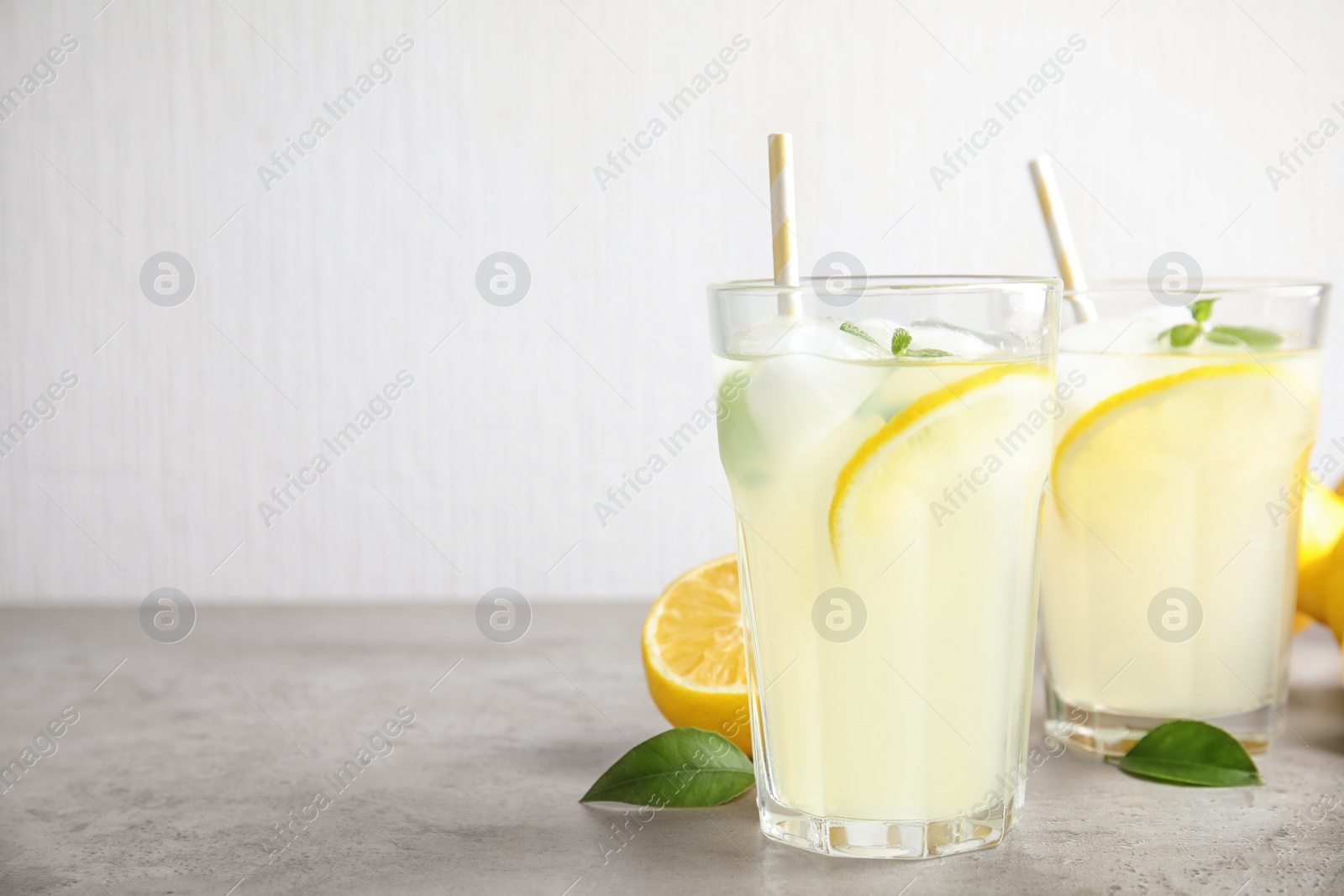 Photo of Glasses of cold lemonade on grey table. Space for text