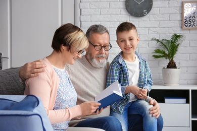 Happy senior couple with little grandson at home