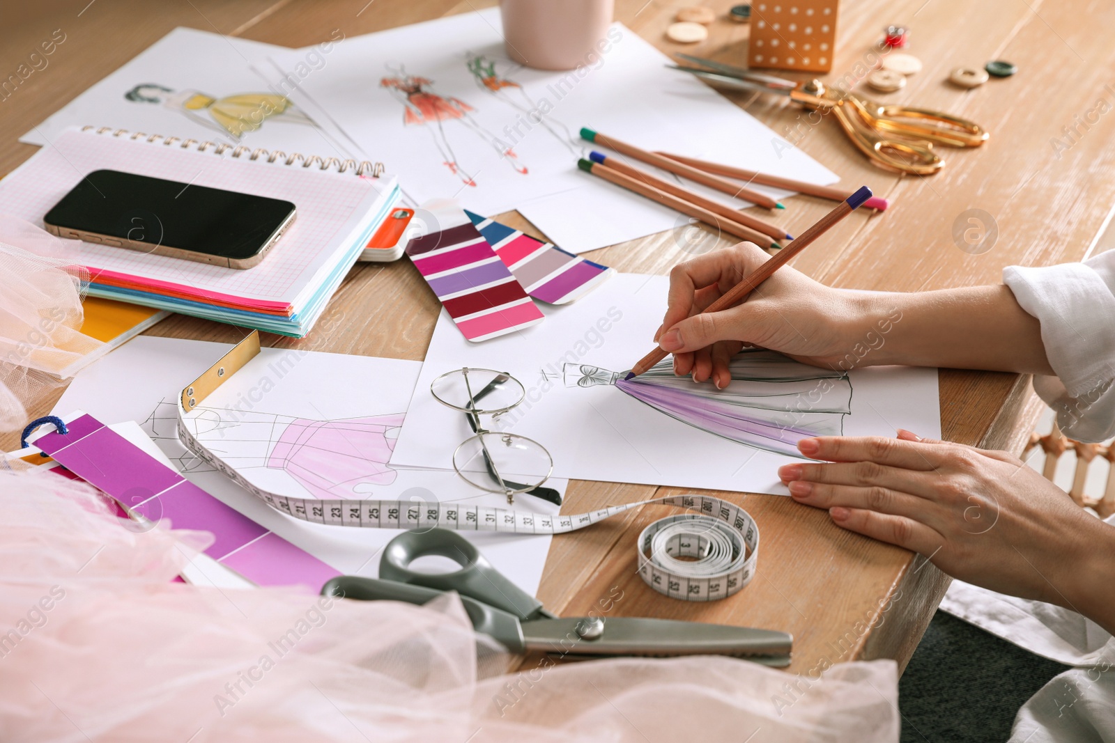 Photo of Fashion designer drawing sketch at wooden table, closeup