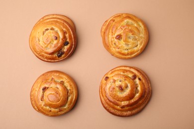 Photo of Delicious rolls with raisins on beige table, flat lay. Sweet buns
