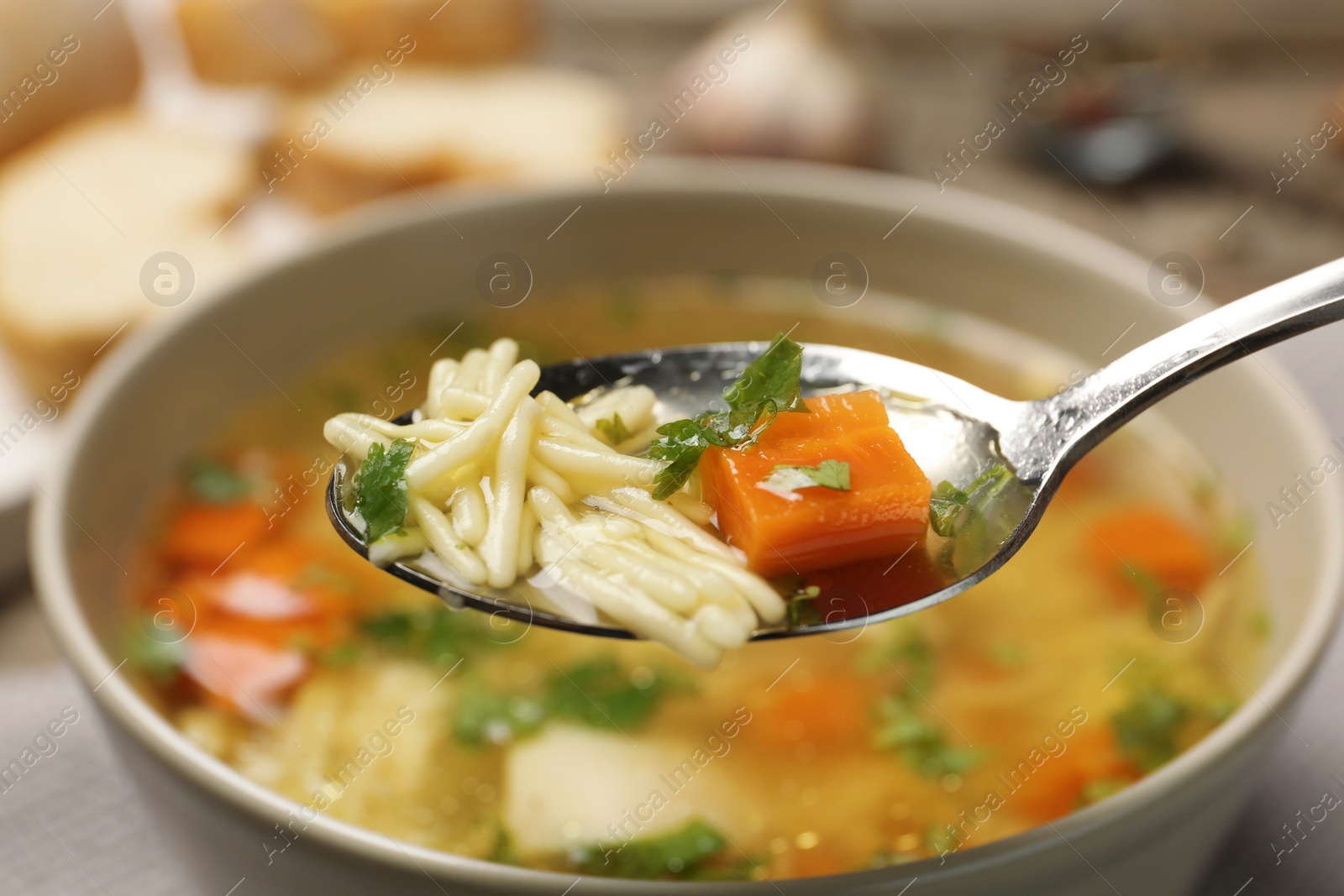 Photo of Spoon with fresh homemade chicken soup on blurred background, closeup