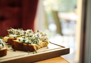 Delicious bruschettas with fish on wooden table, closeup