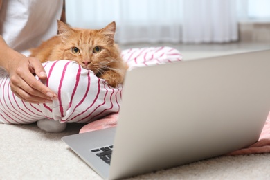 Photo of Woman with cute red cat and laptop at home, closeup view. Space for text
