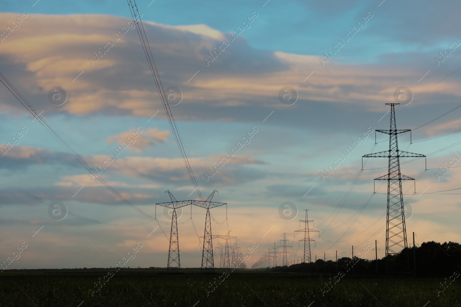 Photo of Telephone poles with cables at sunset outdoors