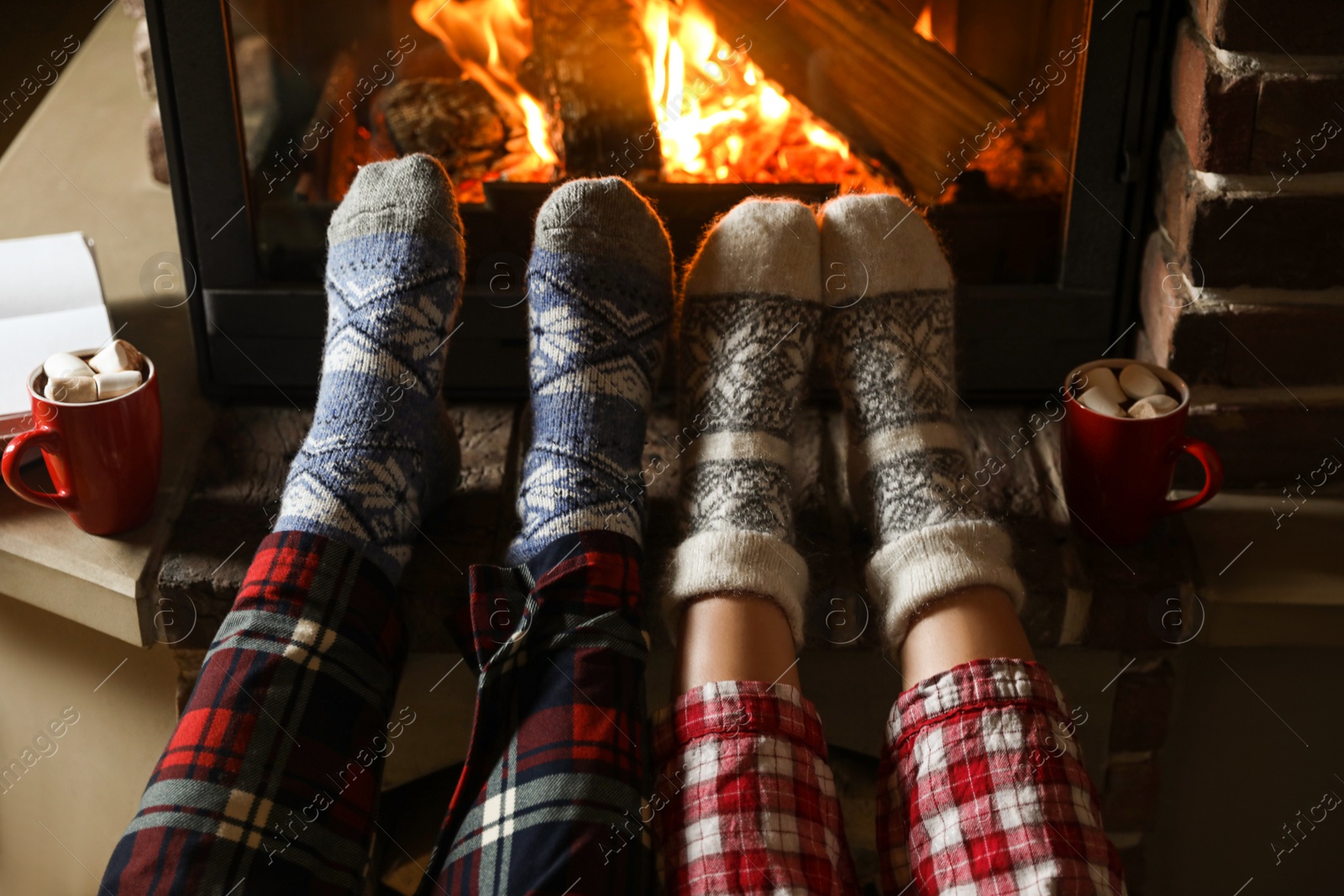 Photo of Couple in pajamas resting near fireplace indoors, closeup. Winter vacation