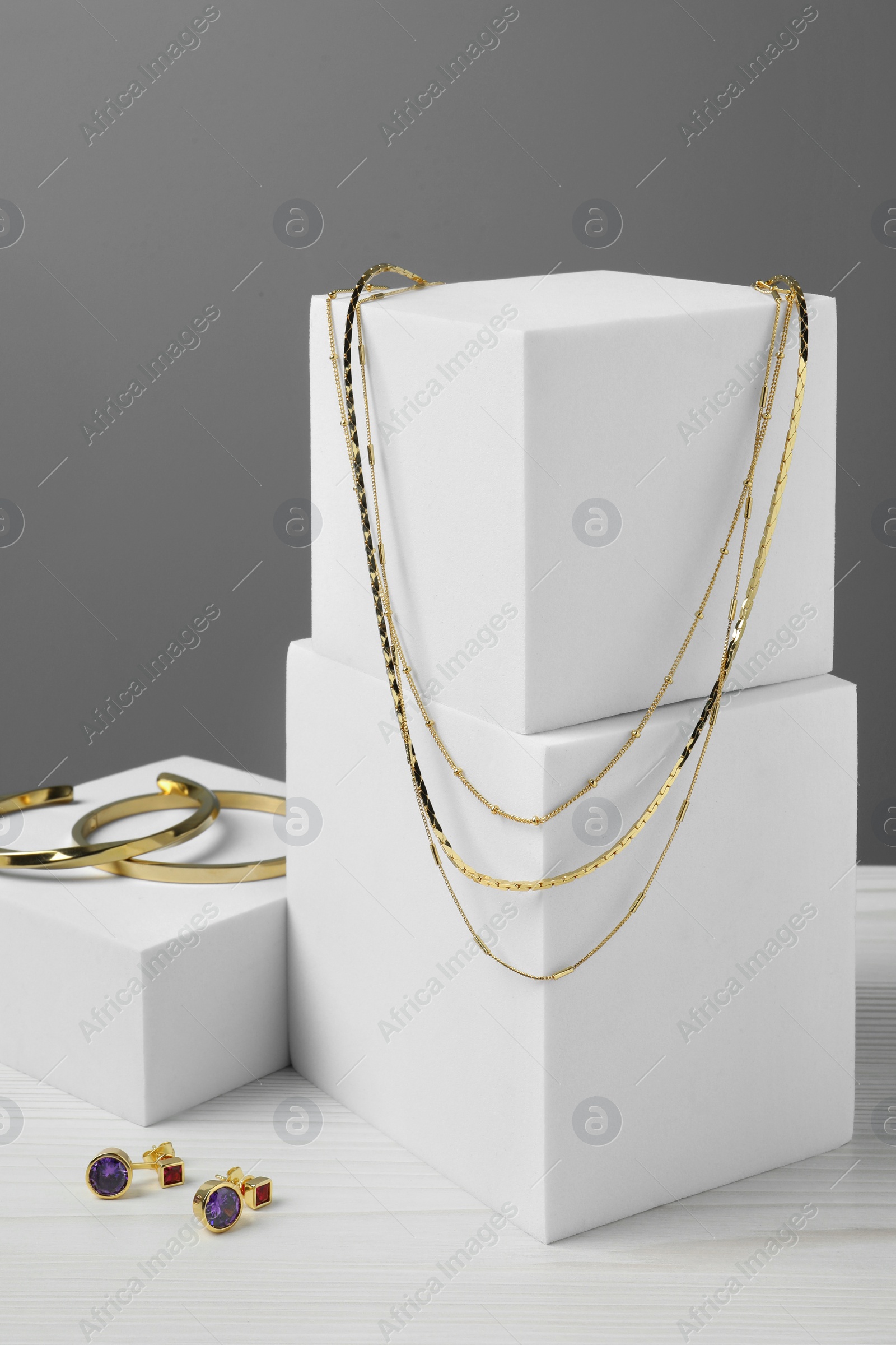 Photo of Stylish presentation of bracelets, necklace and earrings on white wooden table