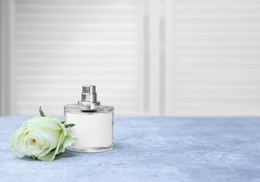 Bottle of perfume and rose on grey table indoors, space for text