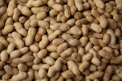 Photo of Many fresh unpeeled peanuts as background, top view