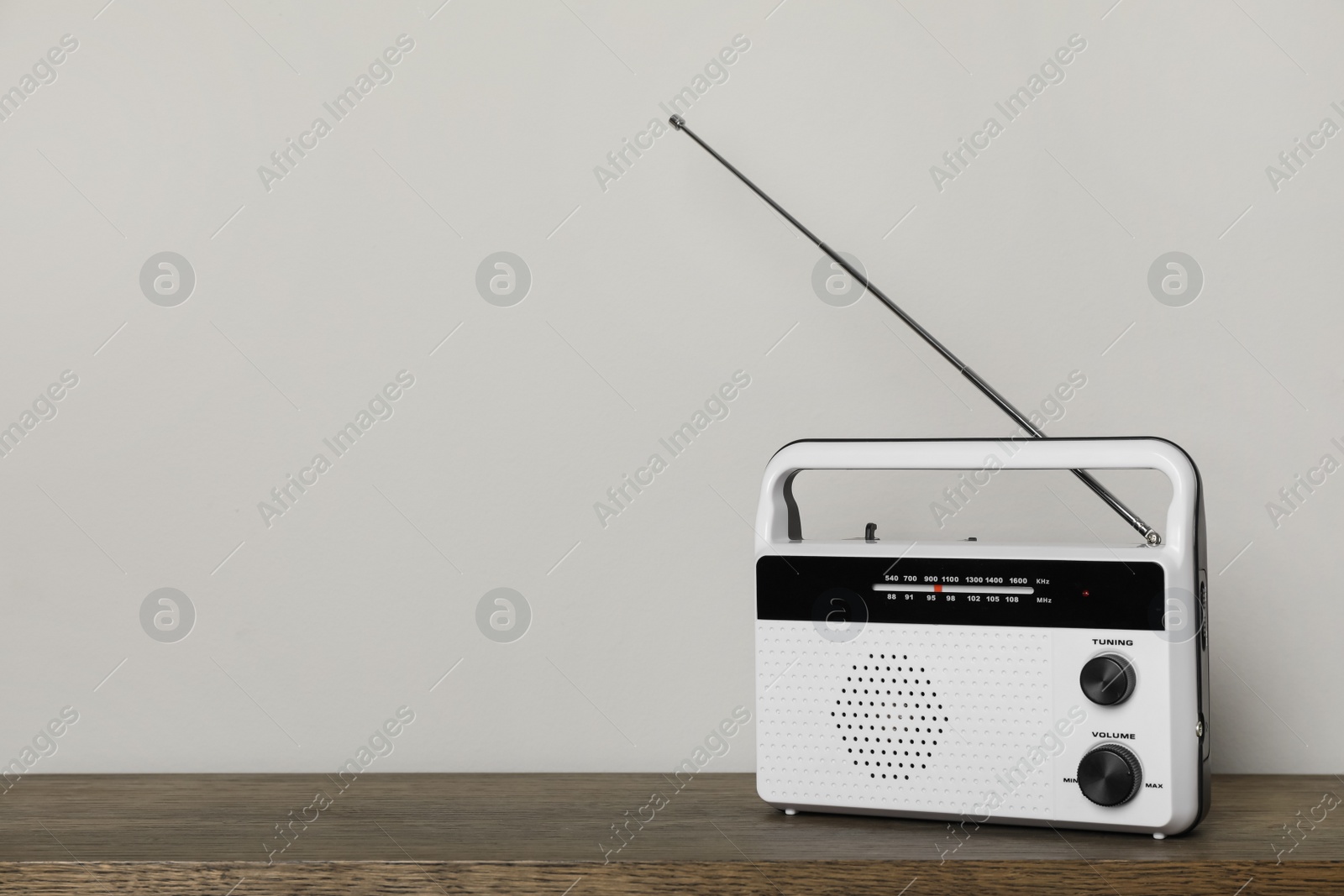 Photo of Retro radio receiver on wooden table against light grey background. Space for text